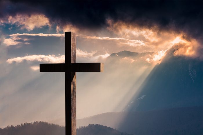 Jesus Christ cross. Christian wooden cross on a background with dramatic lighting, colorful sunset, twilight and orange -  purple clouds and sky.  Easter, resurrection,Good Friday concept